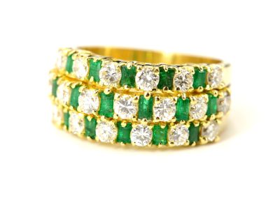 Edelsteinring aus Gelbgold mit hellgrünen Smaragden und Diamanten in drei übereinander liegenden Reihen angeordnet.